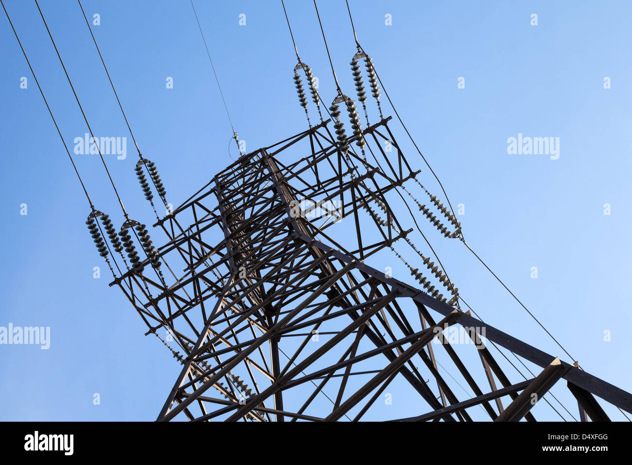 High voltage power lines and big pylon in front of clear blue sky Stock Photo