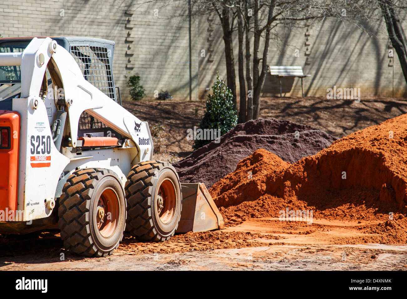 Small earth mover digging in pile of dirt at site Stock Photo