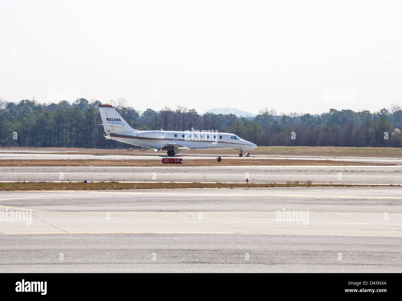 A white Cessna Citation turbo-fan jet taxiing down a runway at a regional airport Stock Photo