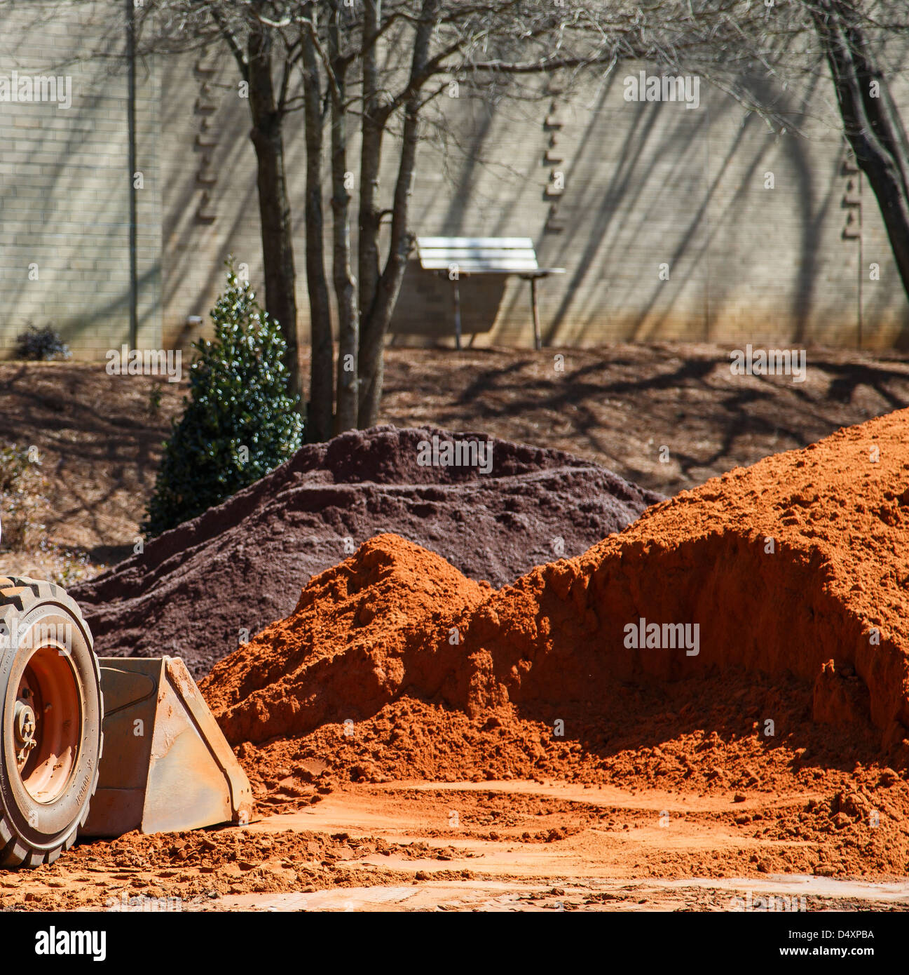 Small earth mover digging in pile of dirt at site Stock Photo