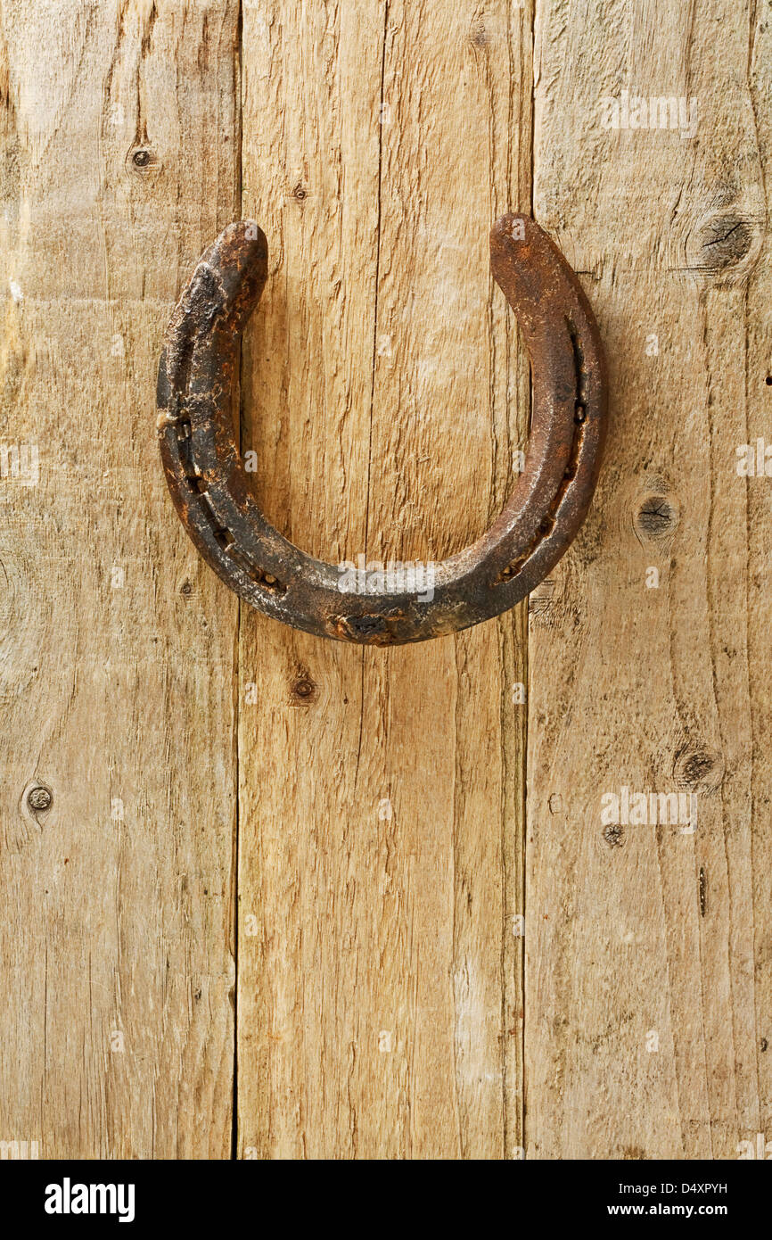 Old rustic horseshoe hanging on door said to bring good fortune and luck according to superstition Stock Photo