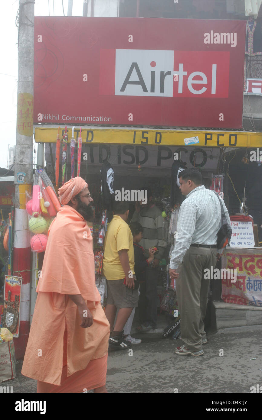 A sadhu passes a phone shop on the Mall in Mussoorie. Stock Photo