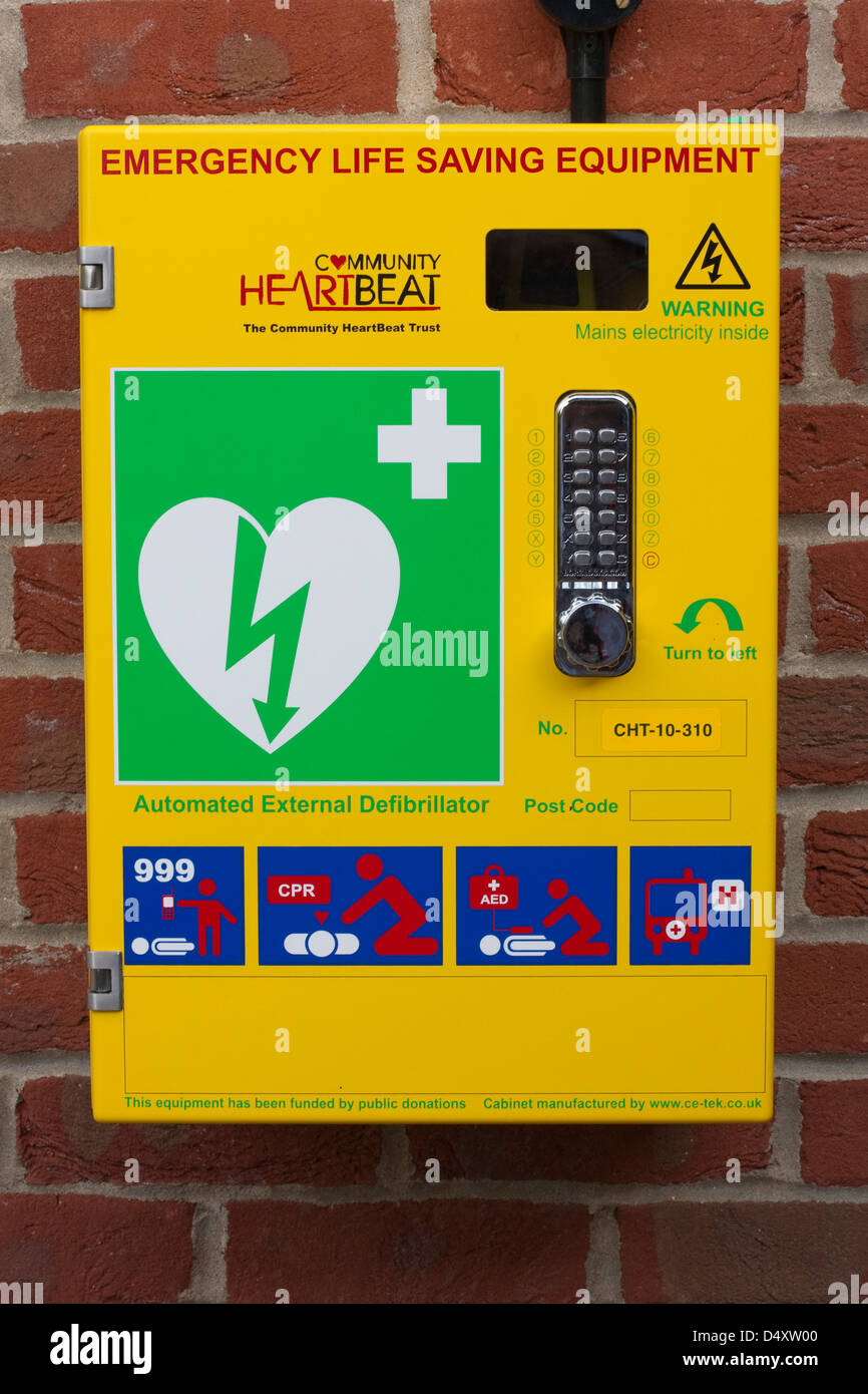 Emergency defibrillator in a bright yellow box on the wall of a sports centre Stock Photo
