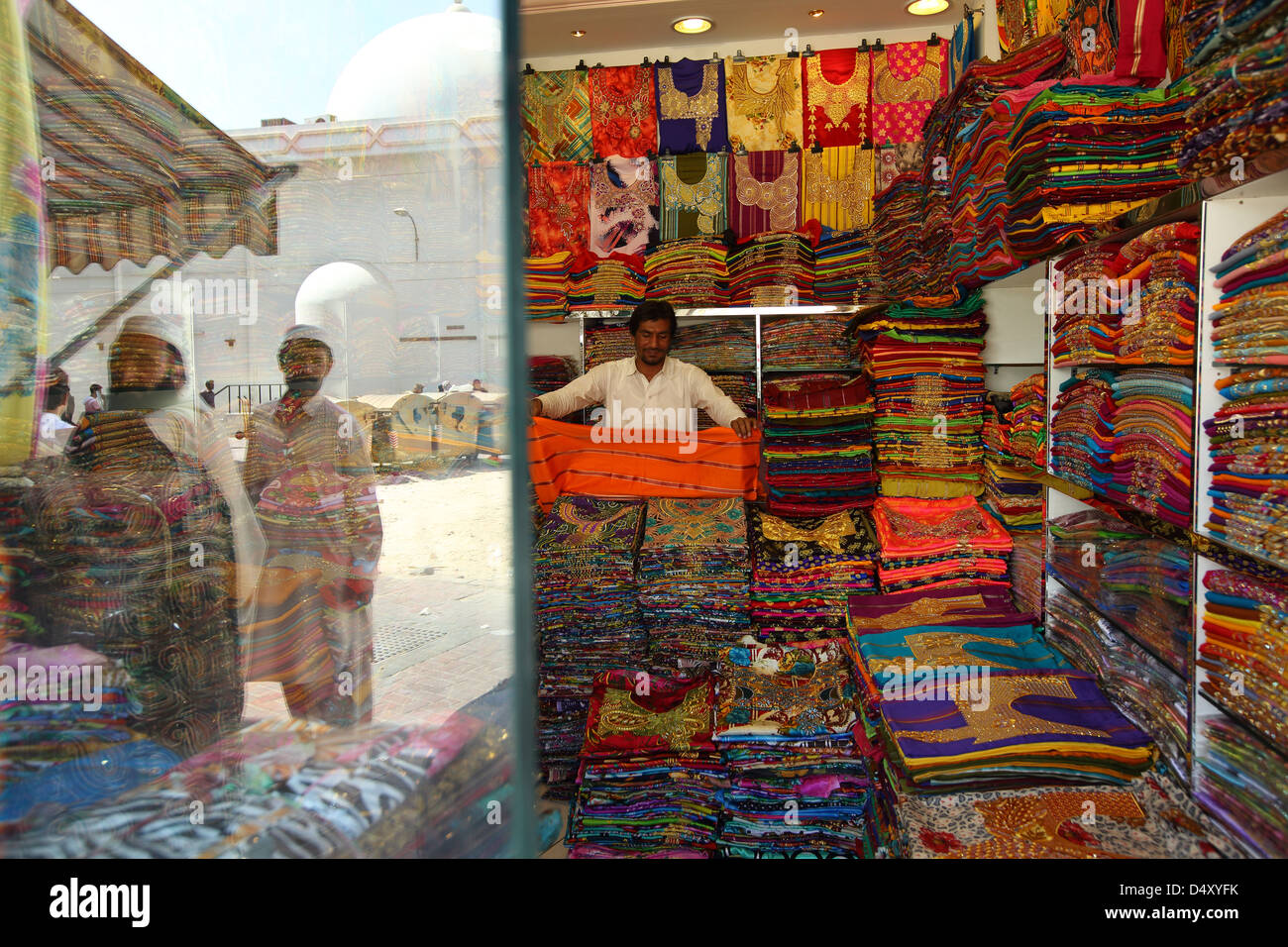 Man folding fabric in textile shop, Dubai, United Arab Emirates Stock Photo