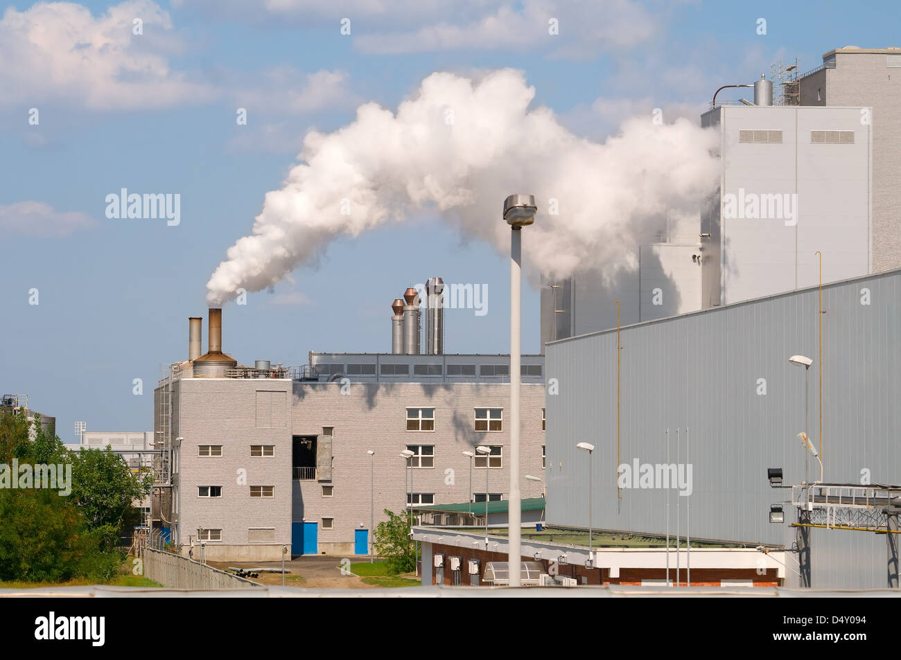 Factory pipes and building on a background of the blue sky with clouds ...