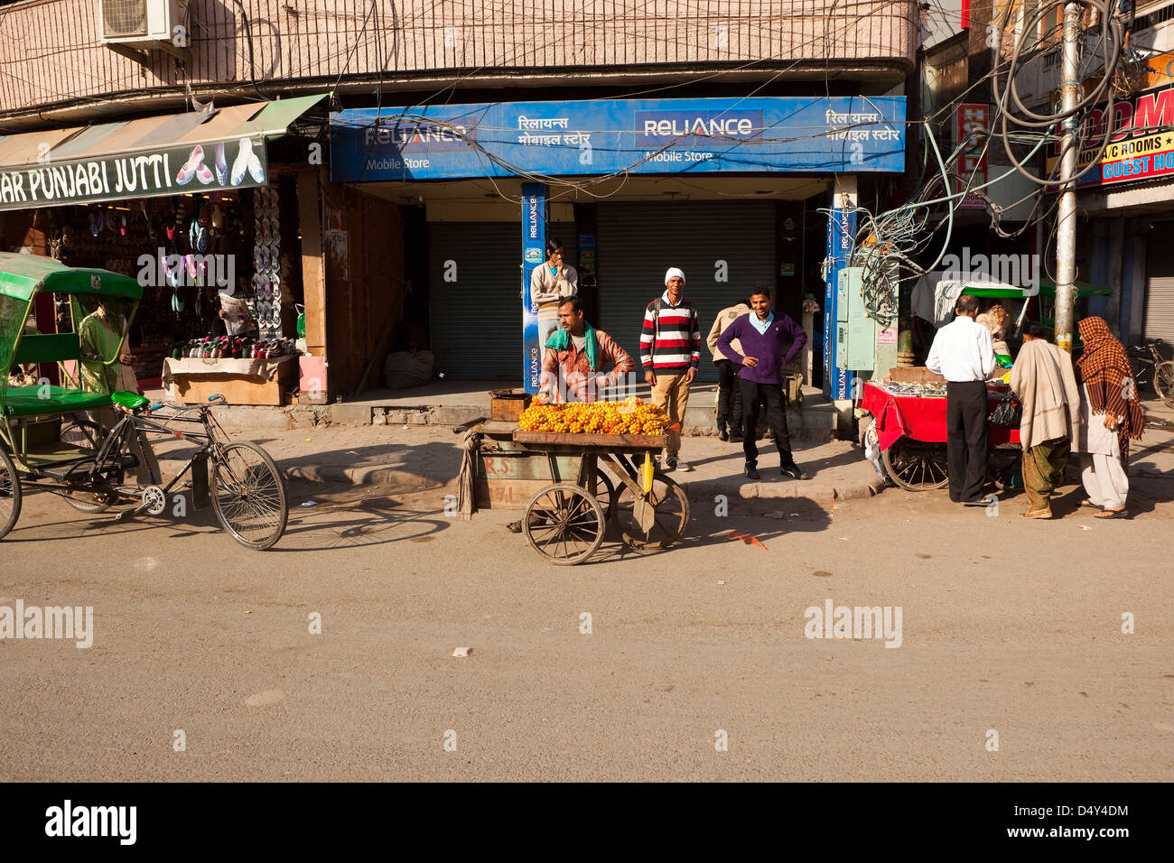 A male Punjabi fruit seller near shops and rickshaws on the streets of Amritsar India Stock Photo