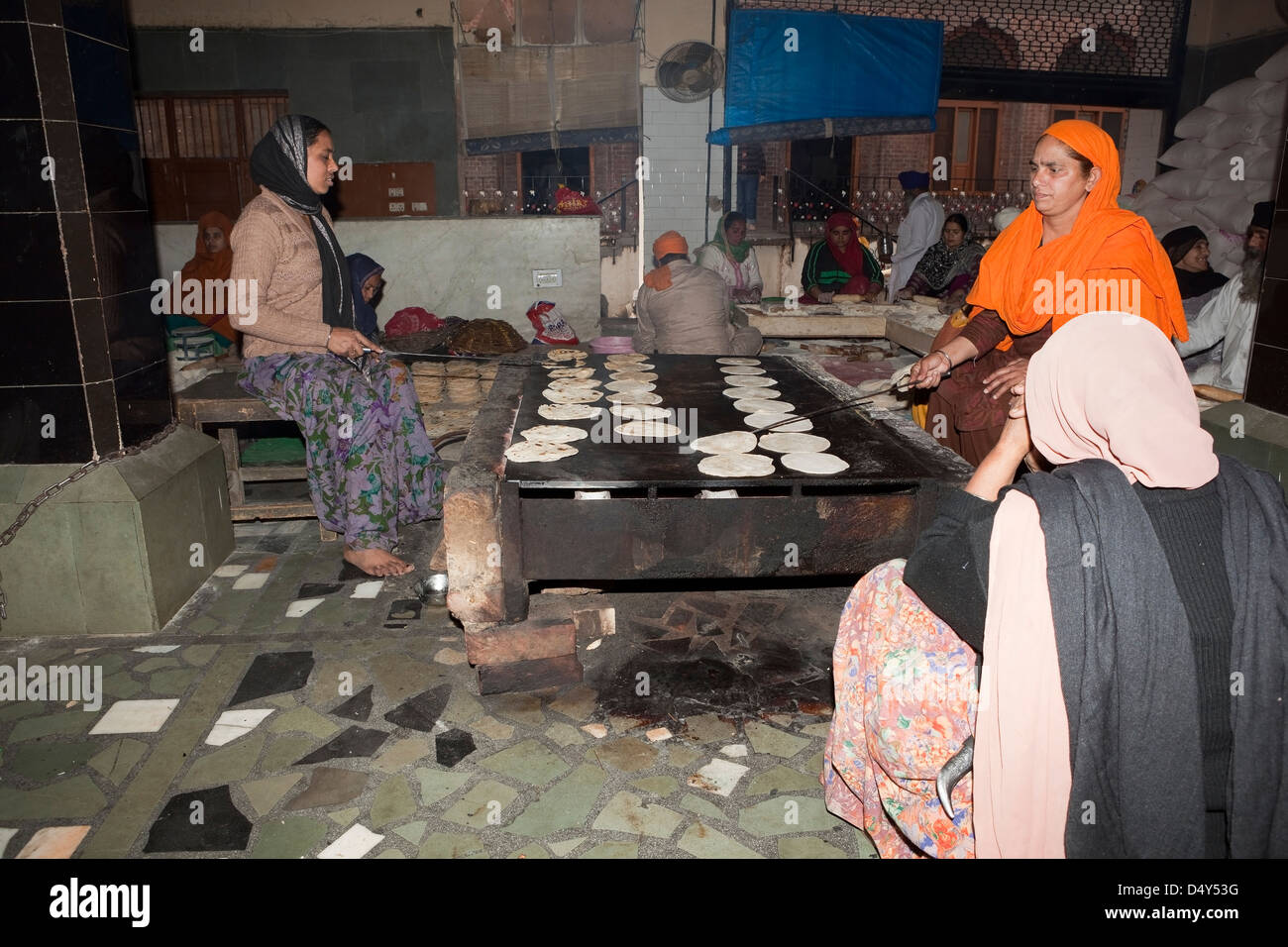 Men and women volunteers making chapattis at the free kitchen inside the Golden Temple complex at Amritsar Punjab India Stock Photo