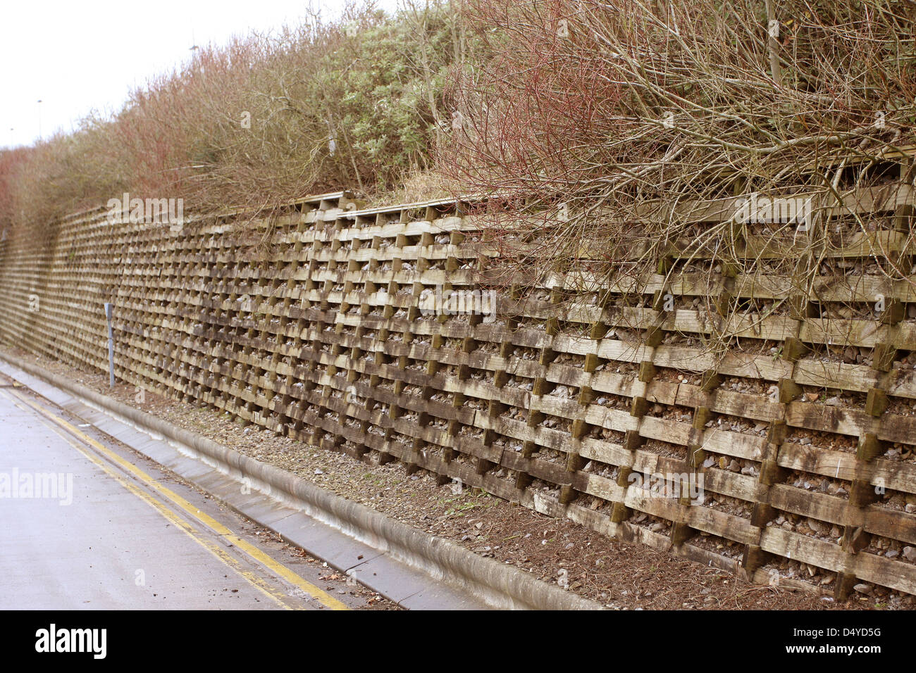 Timber crib lock retaining wall holding back an earth bank beside the service road of a major retail park Stock Photo