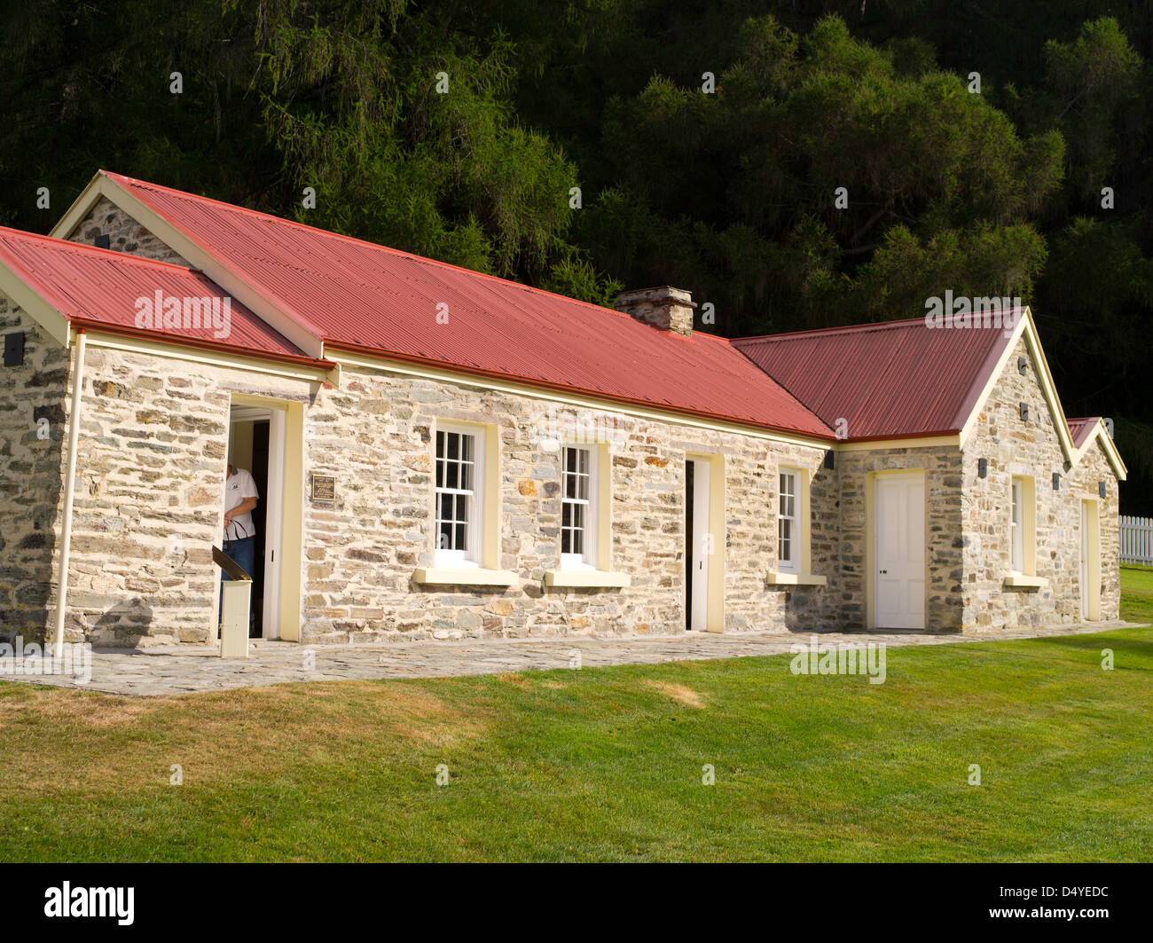 A tourist (woman) explores the historic Skipper's Point School, near Queenstown, Otago, New Zealand. Stock Photo