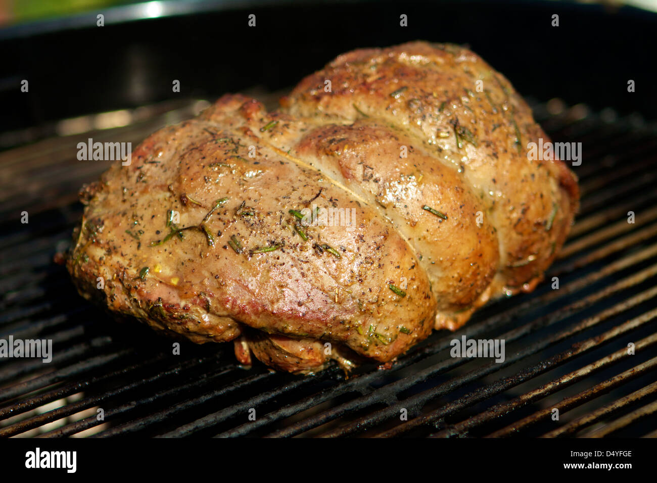 A marinated Leg of Lamb cooking on a outside charcoal barbecue Stock