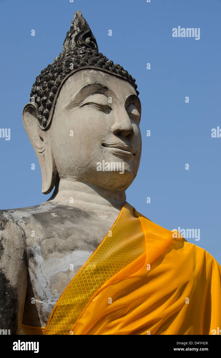 Thailand, Ayutthaya. Wat Phra Chao Phya-thai (aka Wat Yi Chai-mongkol). Seated Buddha statue dressed in yellow robe. UNESCO Stock Photo