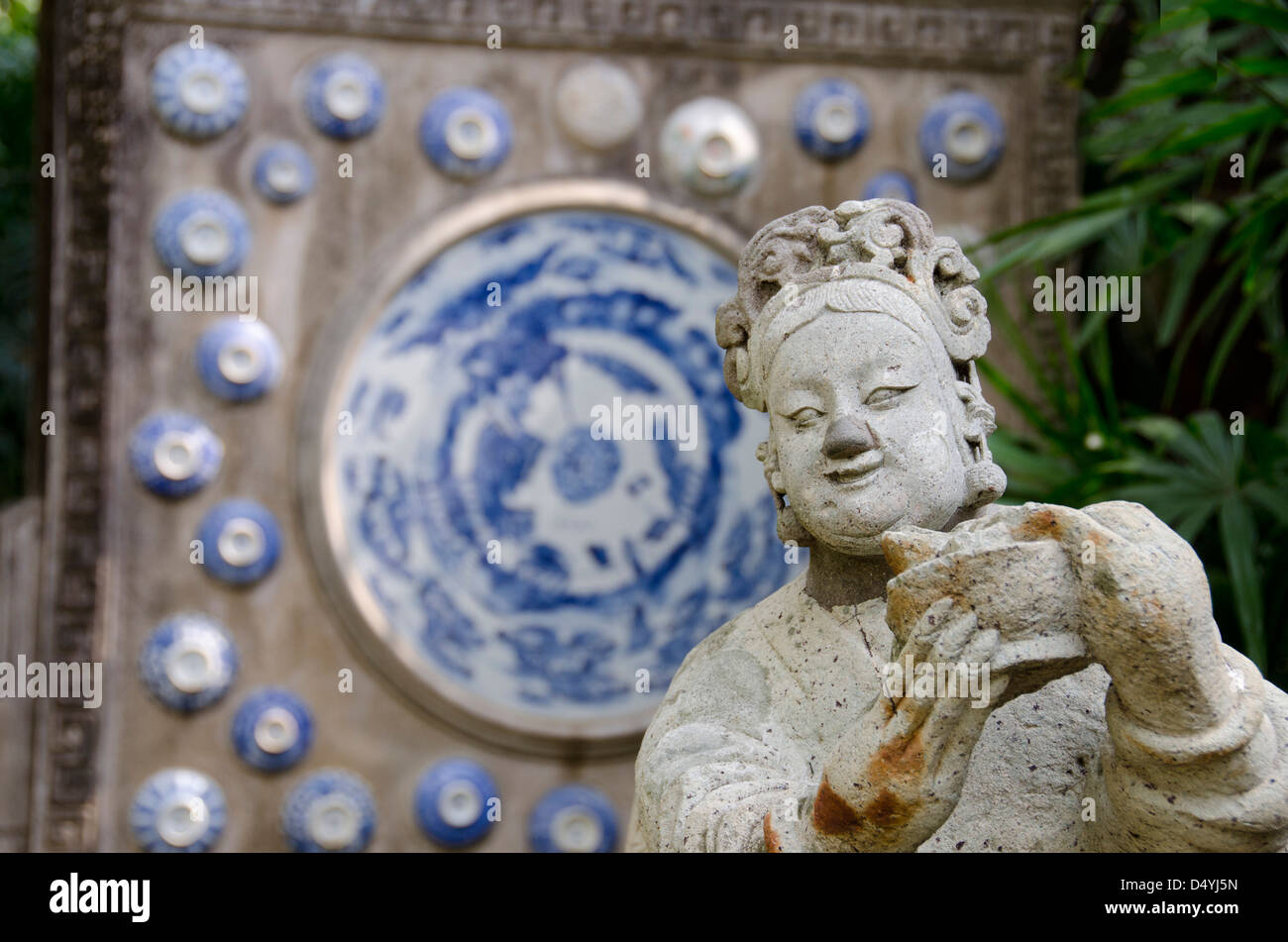 Thailand, Bangkok. The Prasart Museum. Asian garden statue in front of traditional blue and white Chinese pottery. Stock Photo