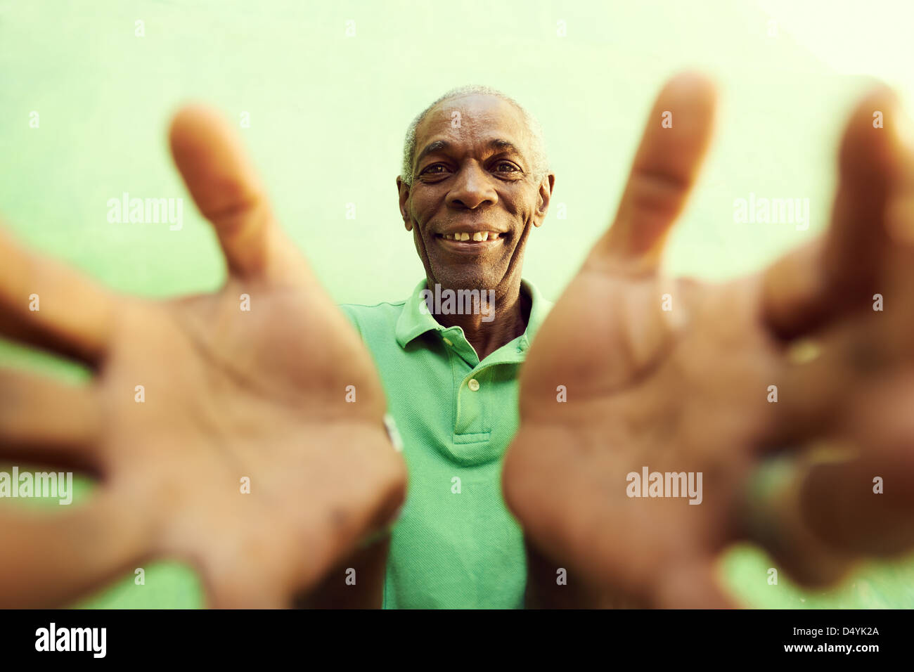 portrait of senior black man with hands and arms open pointing at camera. Green background Stock Photo