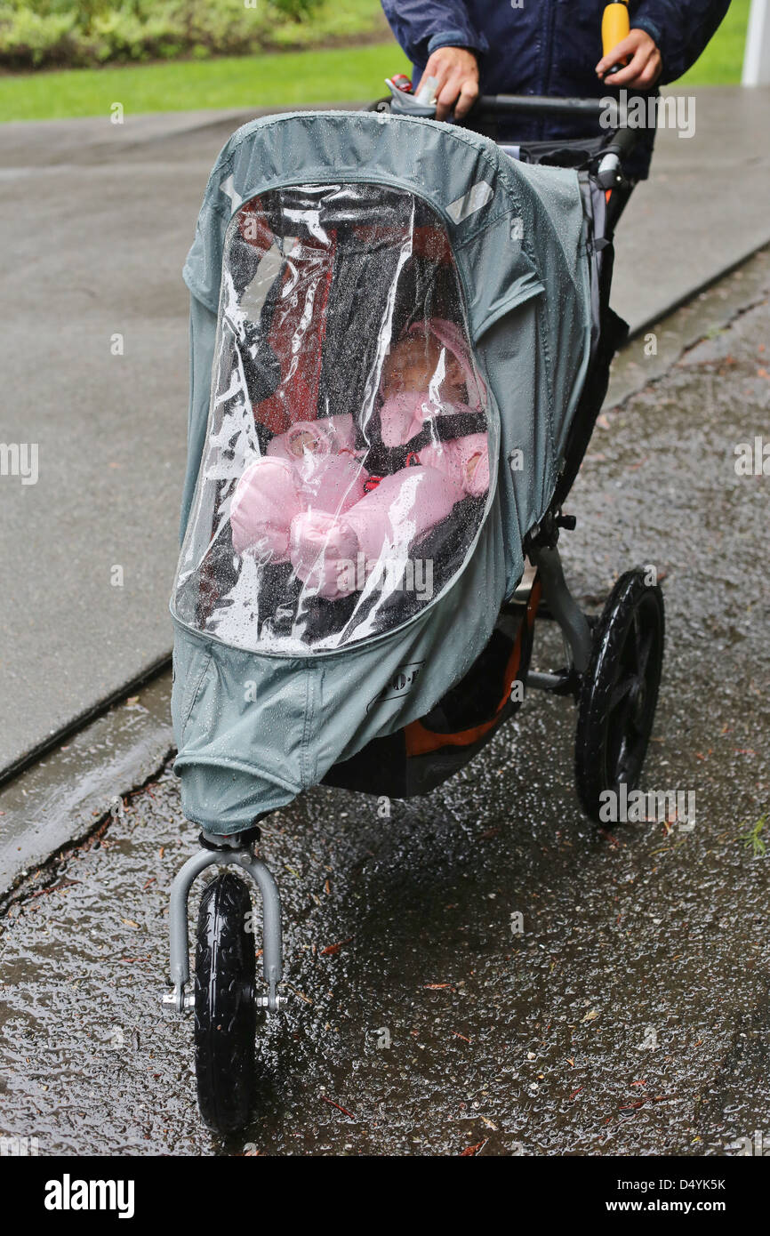 A baby being pushed in a covered stroller on a rainy day. Stock Photo