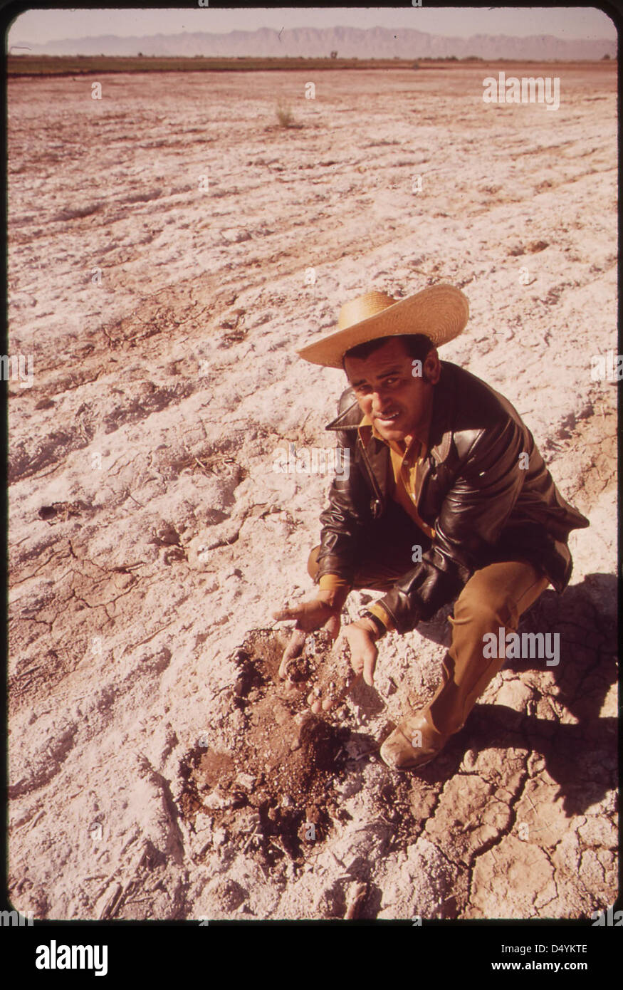 Poor soil, damaged by accumulated salt, is examined by Mexican farmer, Gilberto Buitierrez Banaga, near Mexicali, Mexico. Mexicans want better quality water from Colorado River. Presently salt content is extremely high at Mexican border, May 1972 Stock Photo