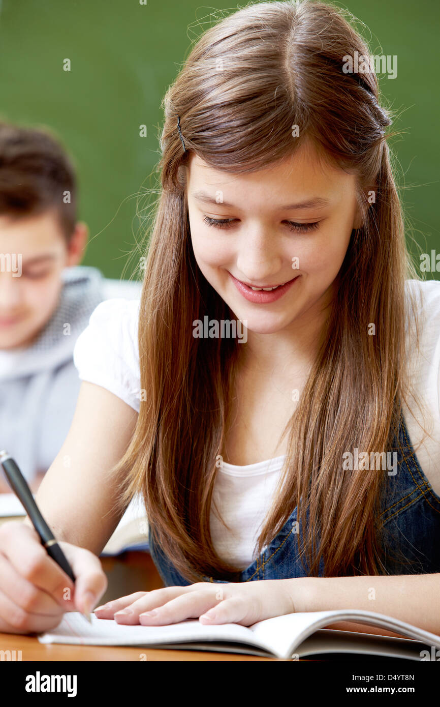 Vertical image of a smiling girl doing her school task Stock Photo