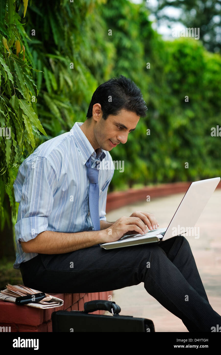 Businessman using a laptop in a park Stock Photo - Alamy