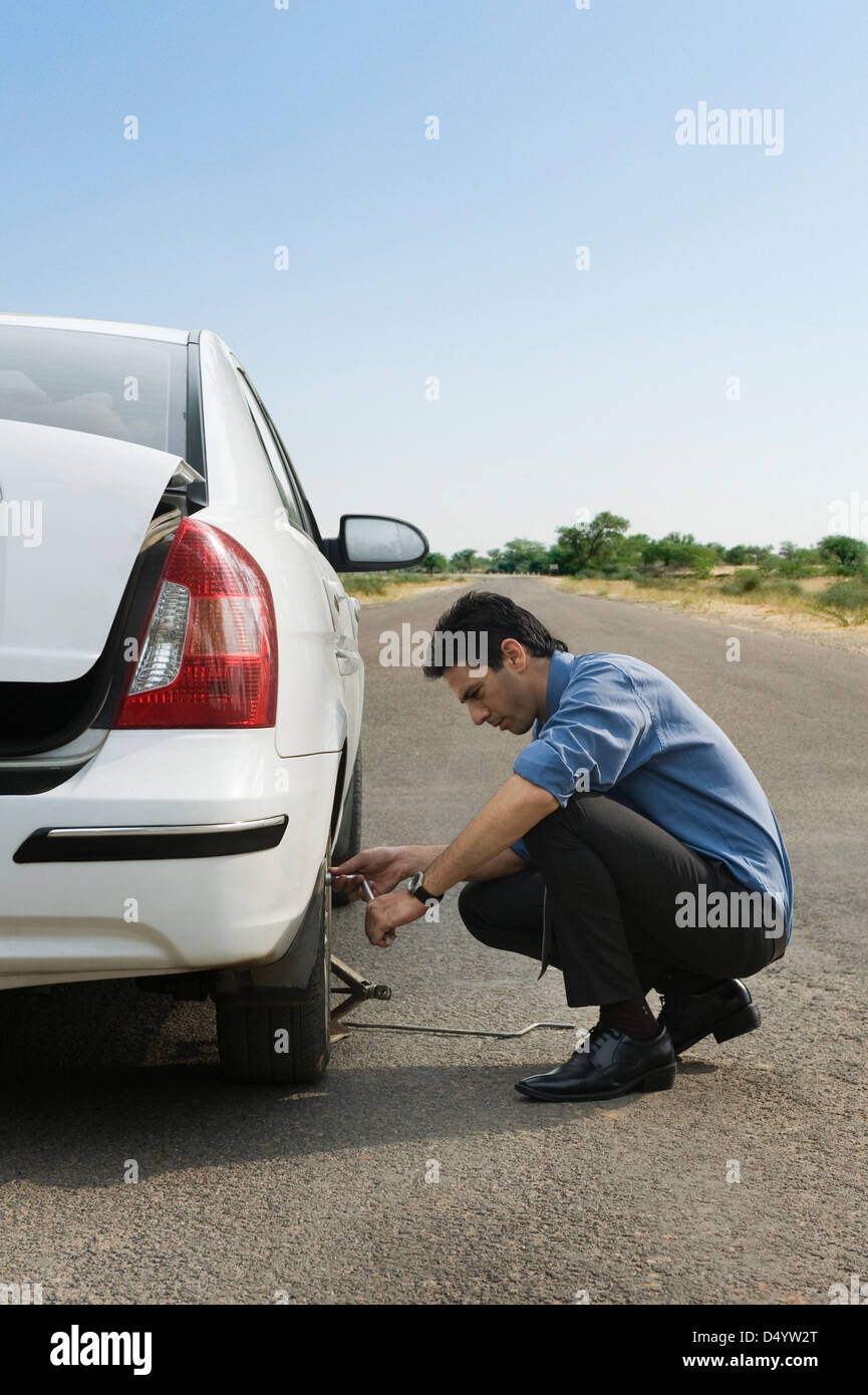 Businessman changing the punctured tire of his car Stock Photo Alamy
