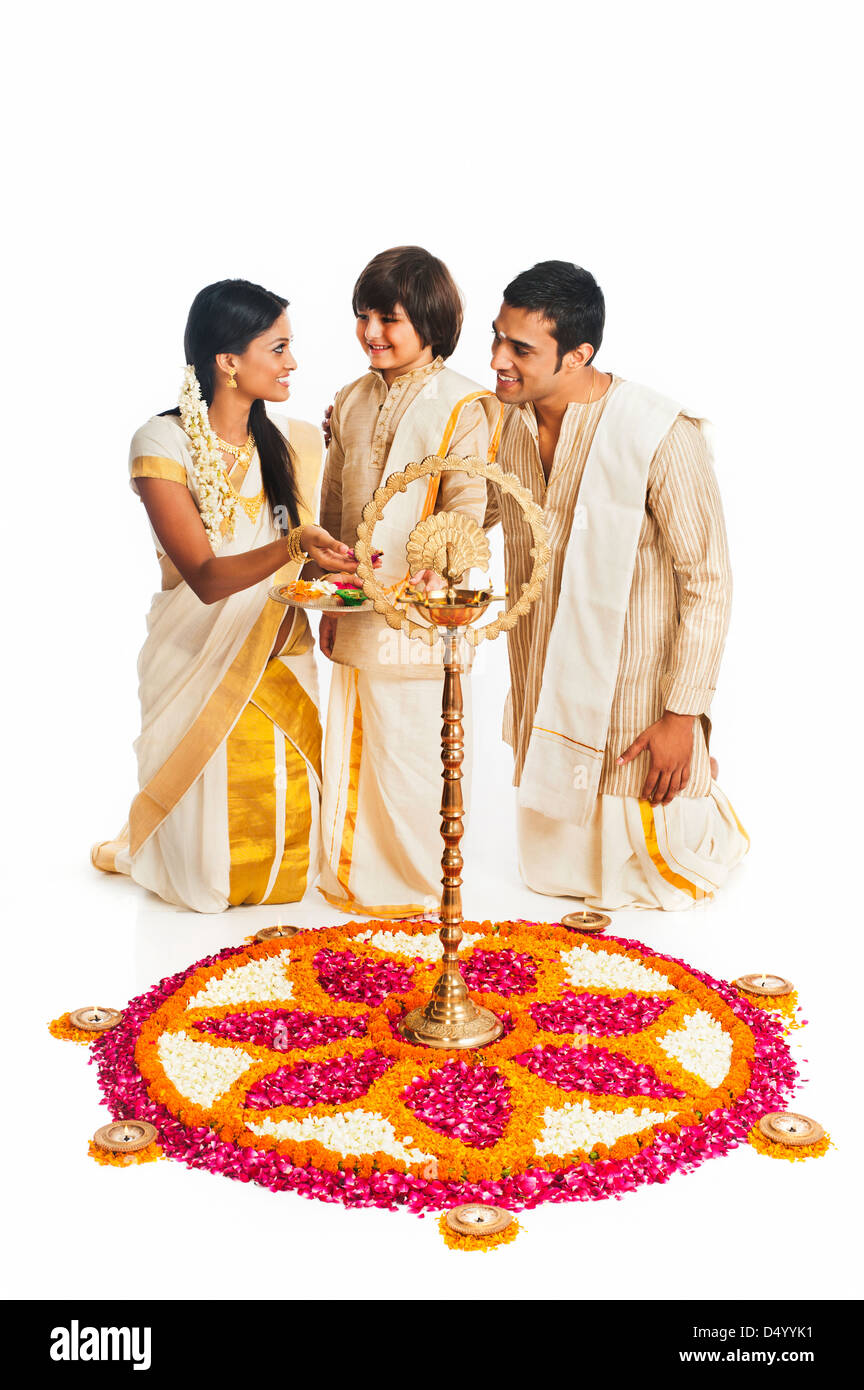 South Indian family standing near rangoli of flowers at Onam Stock Photo