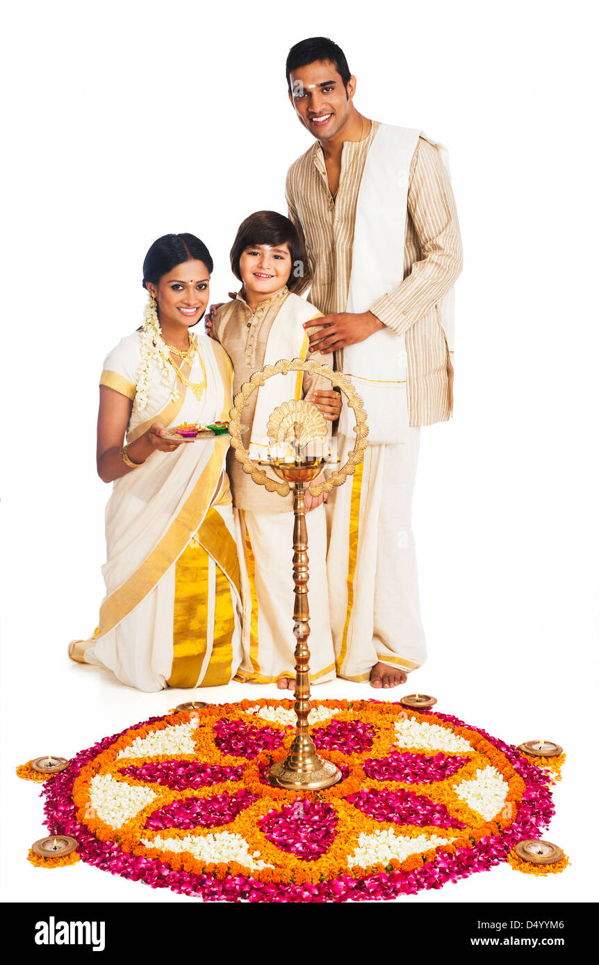 South Indian family standing near rangoli of flowers at Onam Stock ...