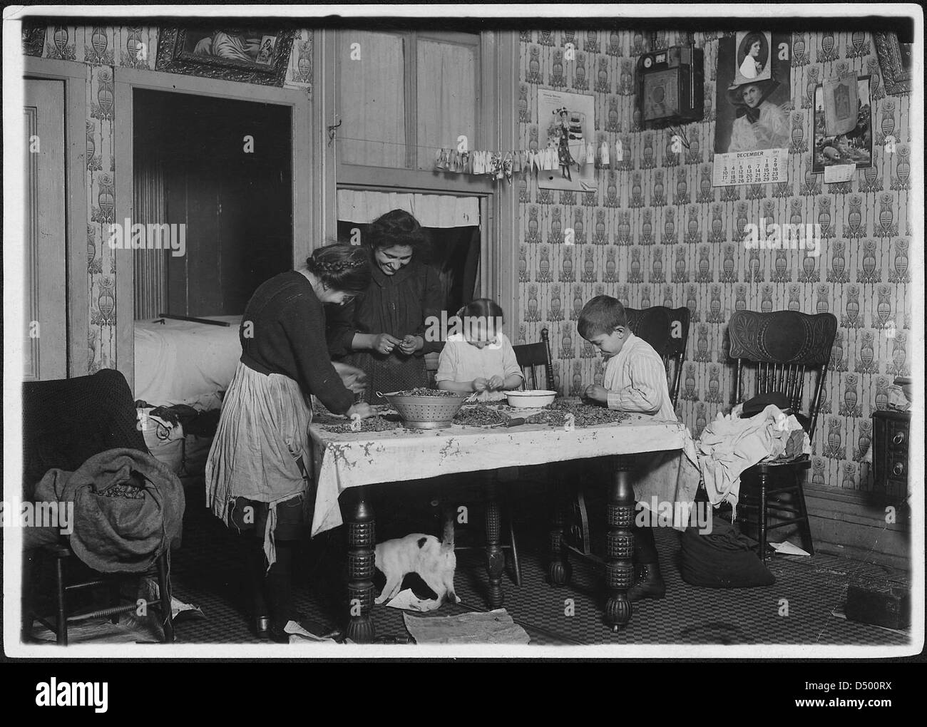 Mrs. Salvia, Joe, 10 years old, Josephine, 14 years, Camille, 7 years, picking nuts in a dirty tenement home, December 1911 Stock Photo