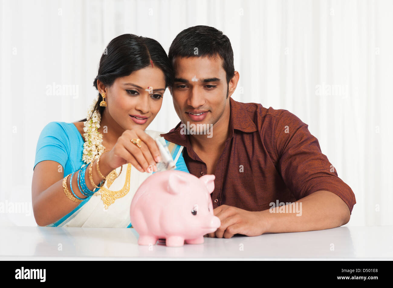 South Indian couple putting cash in a piggy bank Stock Photo - Alamy