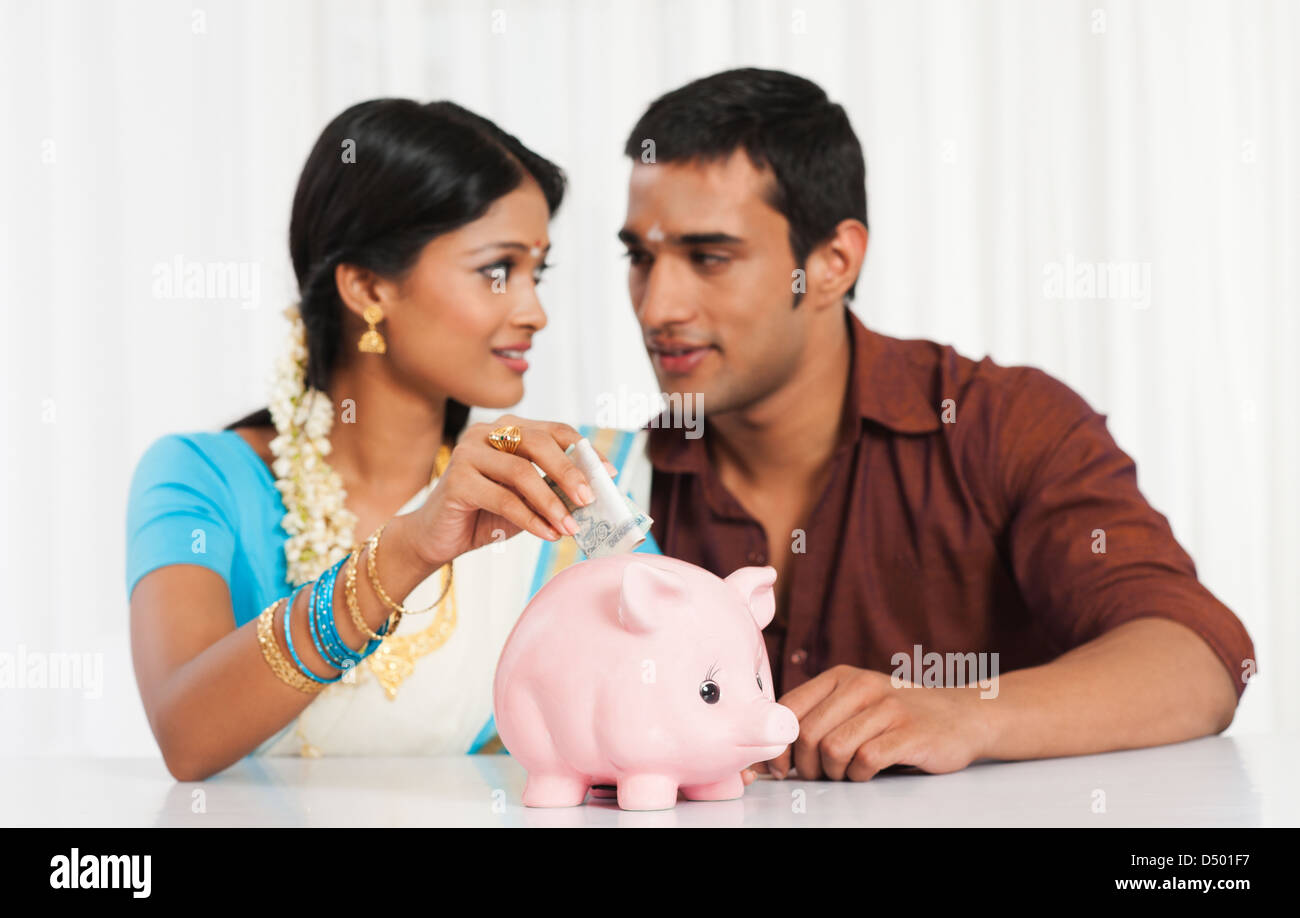 South Indian couple putting cash in a piggy bank Stock Photo - Alamy