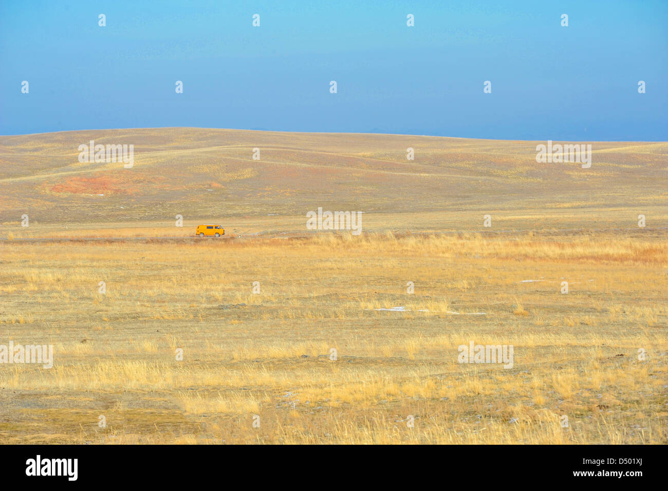 Steppe landscape with a moving orange car Stock Photo