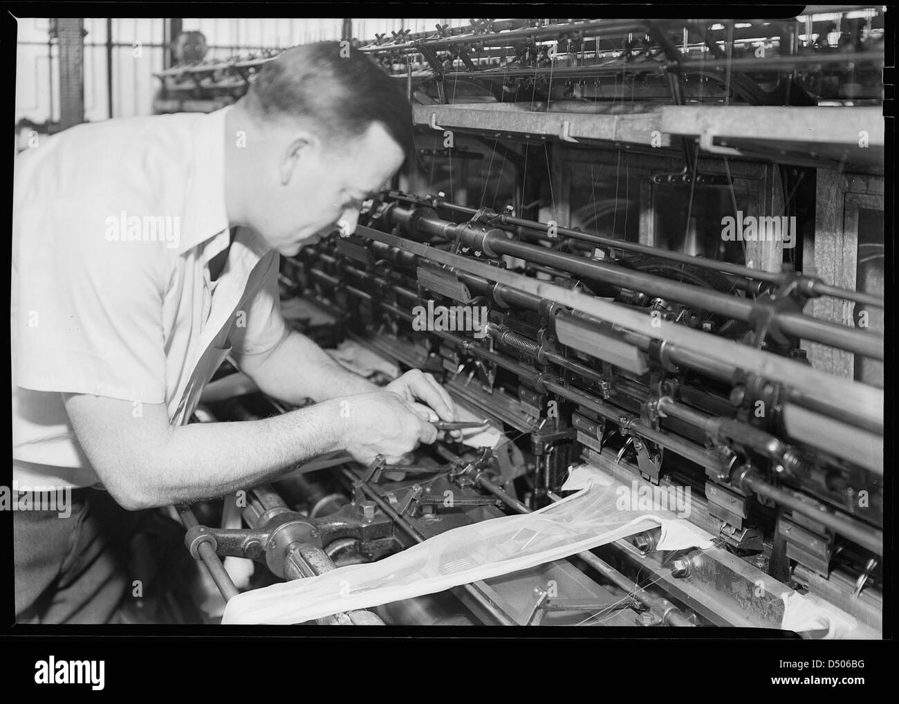 Man snipping at stockings on machine, 1936 Stock Photo