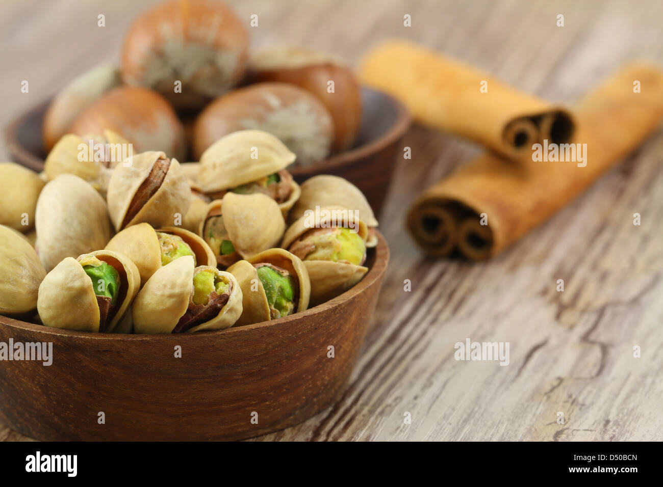 Pistachios, hazelnuts and cinnamon sticks on wooden background Stock