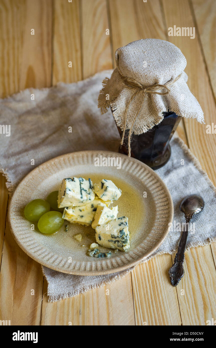 Rustic jam pot, plate of blue mold camembert cheese and grapes standing on wooden table Stock Photo