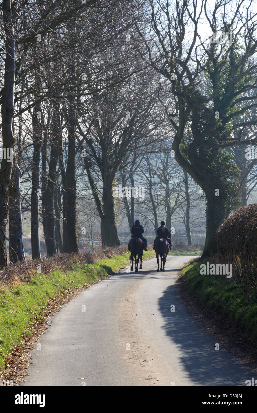 Two horseriders riding along a country lane in Hampshire Stock Photo