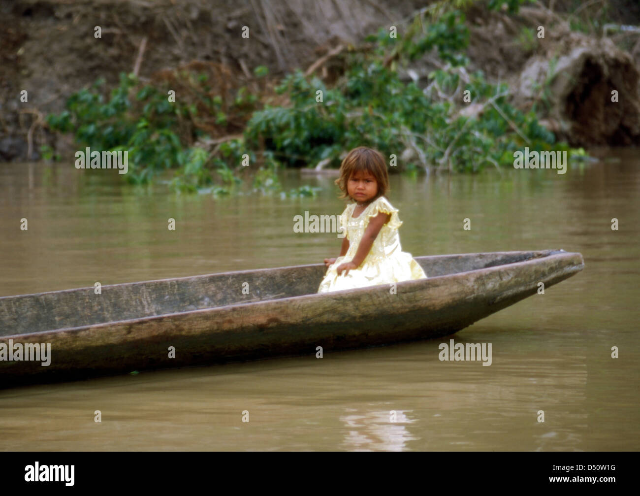 Small Girl Sitting In A Dugout Canoe On The Amazon River Peru Stock