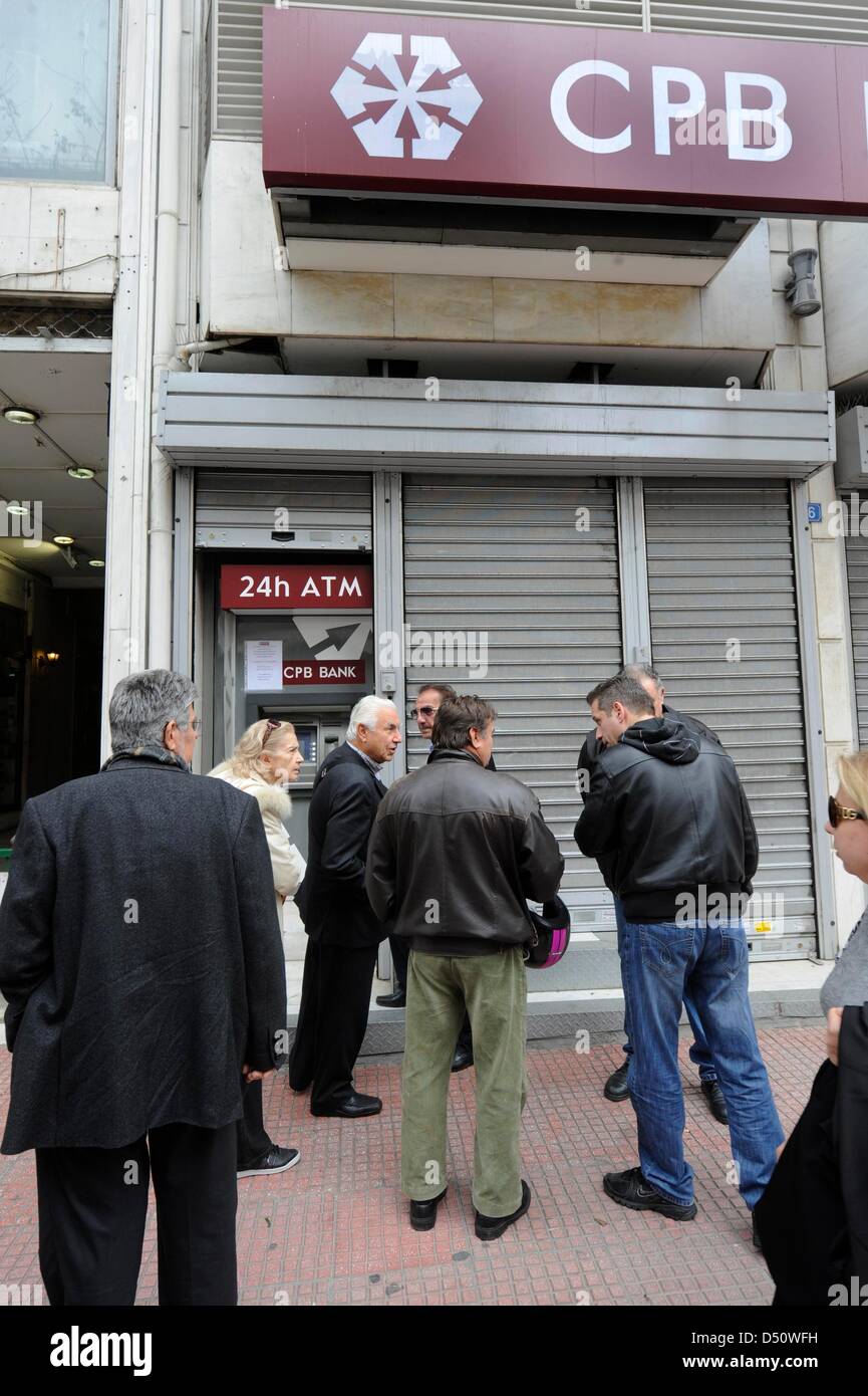 People wait to use the ATM in front of a closed branch of CPB Bank (Cypriot Popular Bank) in Athens, Greece, Giorgos Nikolaidis Stock Photo