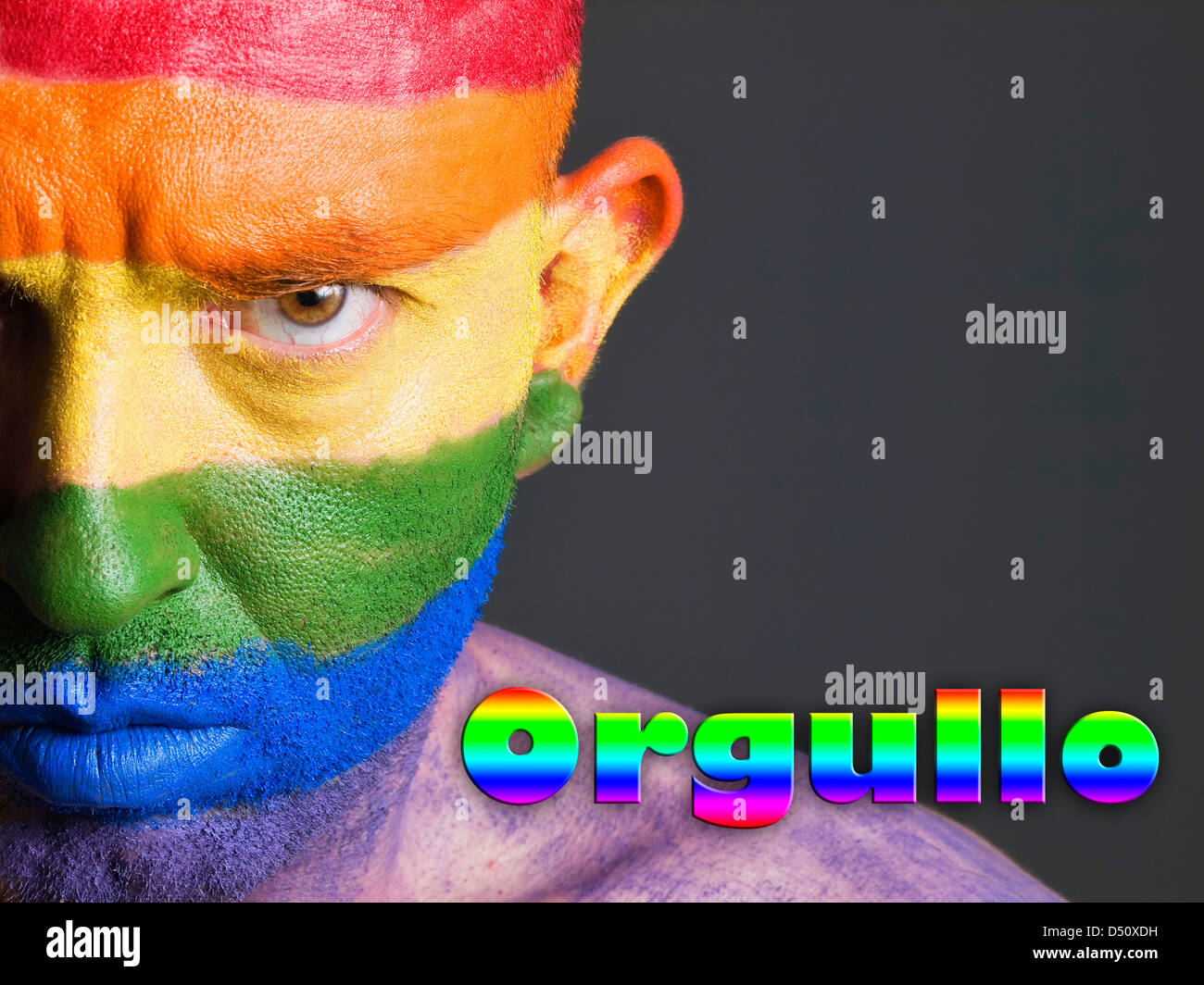 Hombre con la bandera gay pintada en la cara y con una expresion seria. La palabra orgullo esta escrita en un lado. Stock Photo