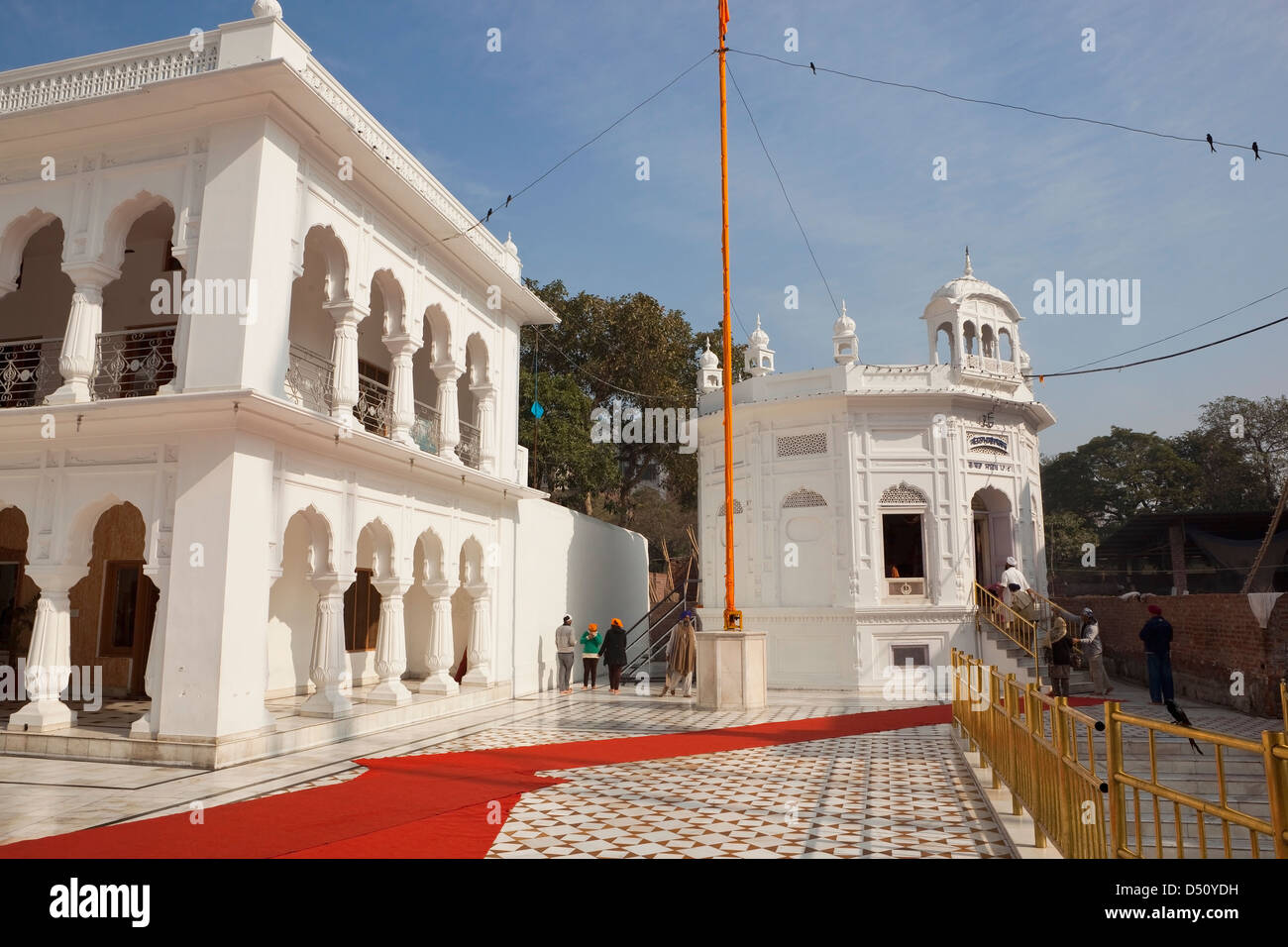 white marble architecture with Sikh pilgrims and flag pole inside the Golden Temple complex Amritsar Punjab India Stock Photo