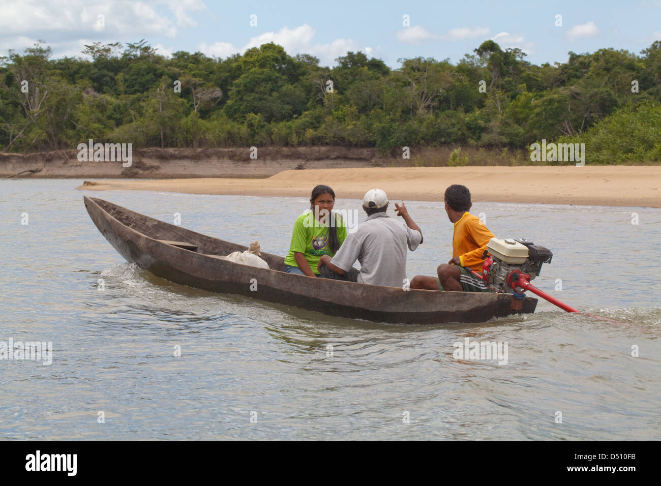 Amerindian villagers in a traditionally made dugout tree trunk canoe propelled by an out-board motor engine. River Essequibo. Stock Photo