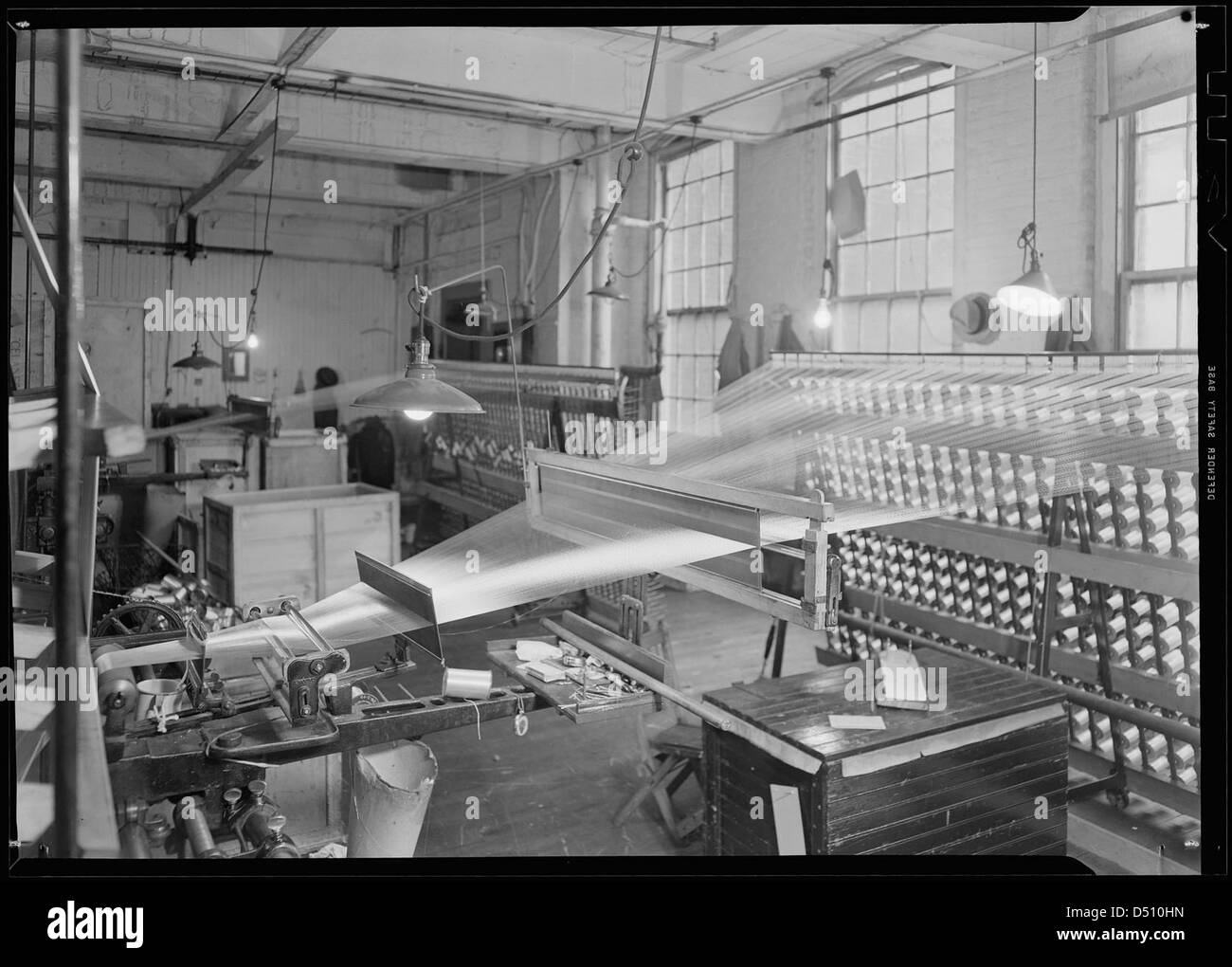 This 1937 photograph shows threads being processed in a factory setting ...