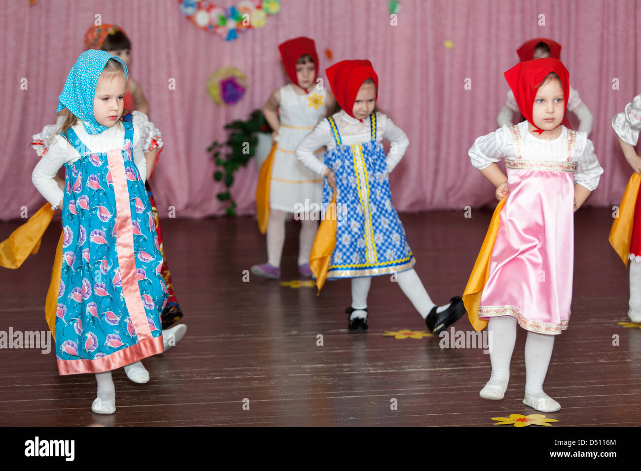 Preschooler girls dancing on the stage in Russian traditional clothes