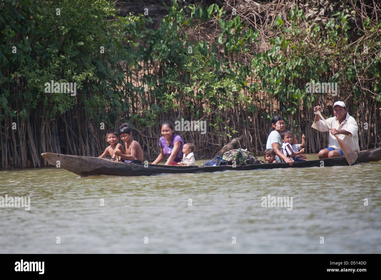 Amerindian family paddling in a dug-out canoe. Relocating from village to cleared forest cultivated plot for summer. River Rewa. Guyana. South America. Stock Photo