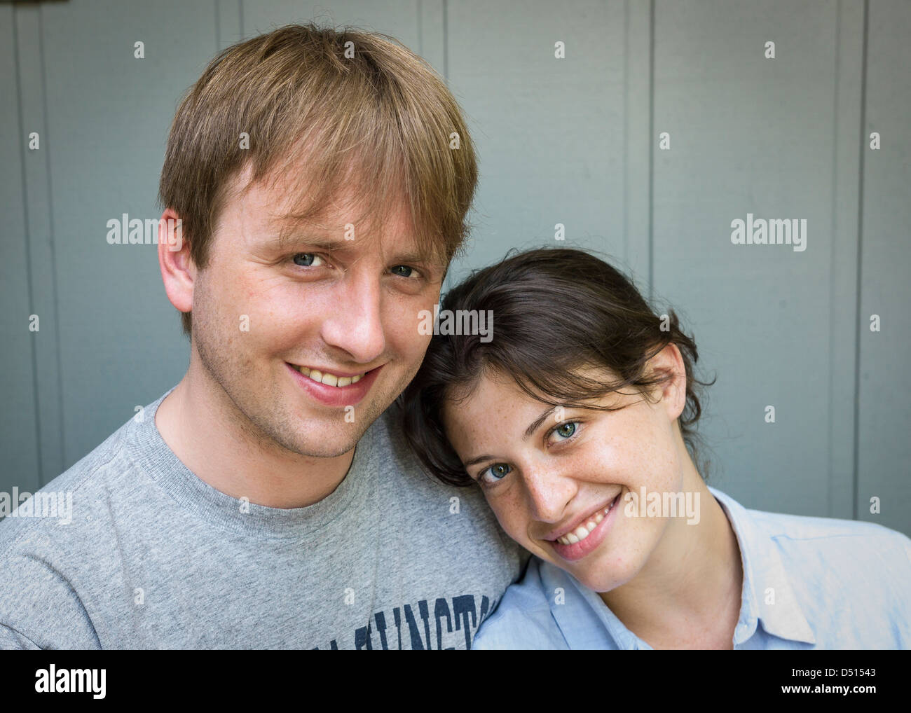 A young, Caucasian couple are smiling looking at the viewer.  The image include their and head and shoulders. Stock Photo