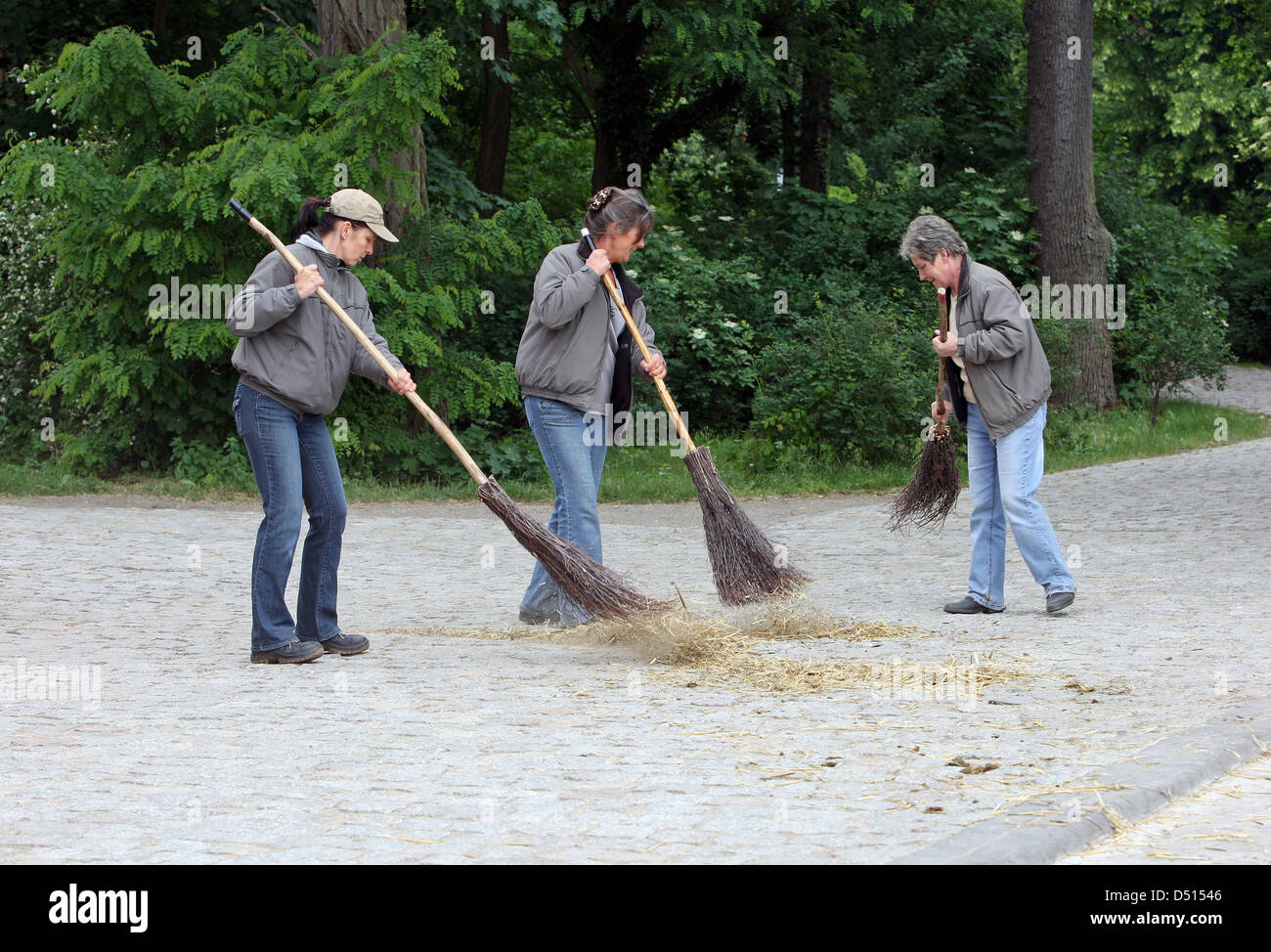 Graditz Germany, women sweep a street with broom Stock Photo