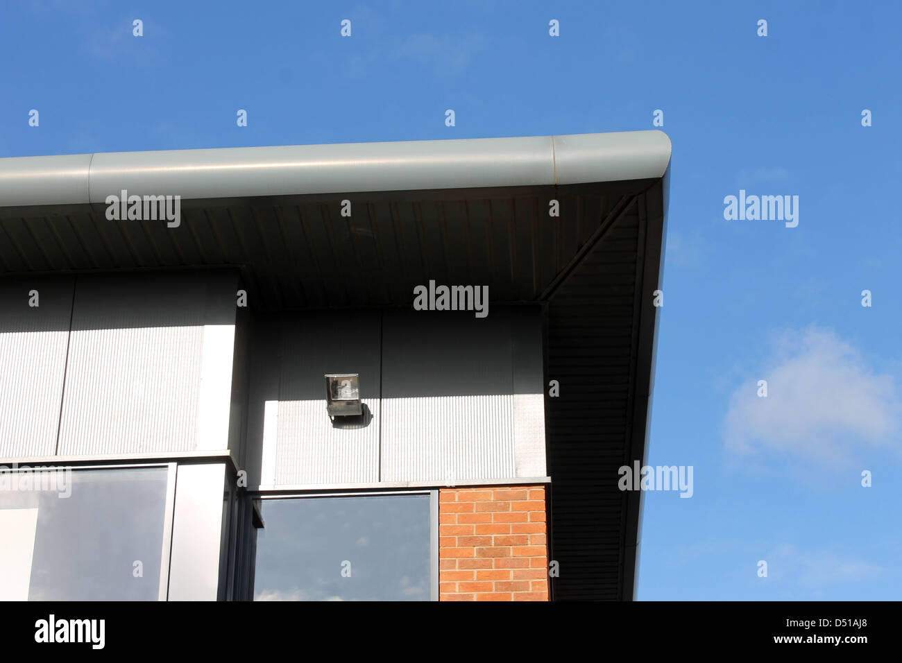Details of modern office building showing roof and windows, blue sky background. Stock Photo