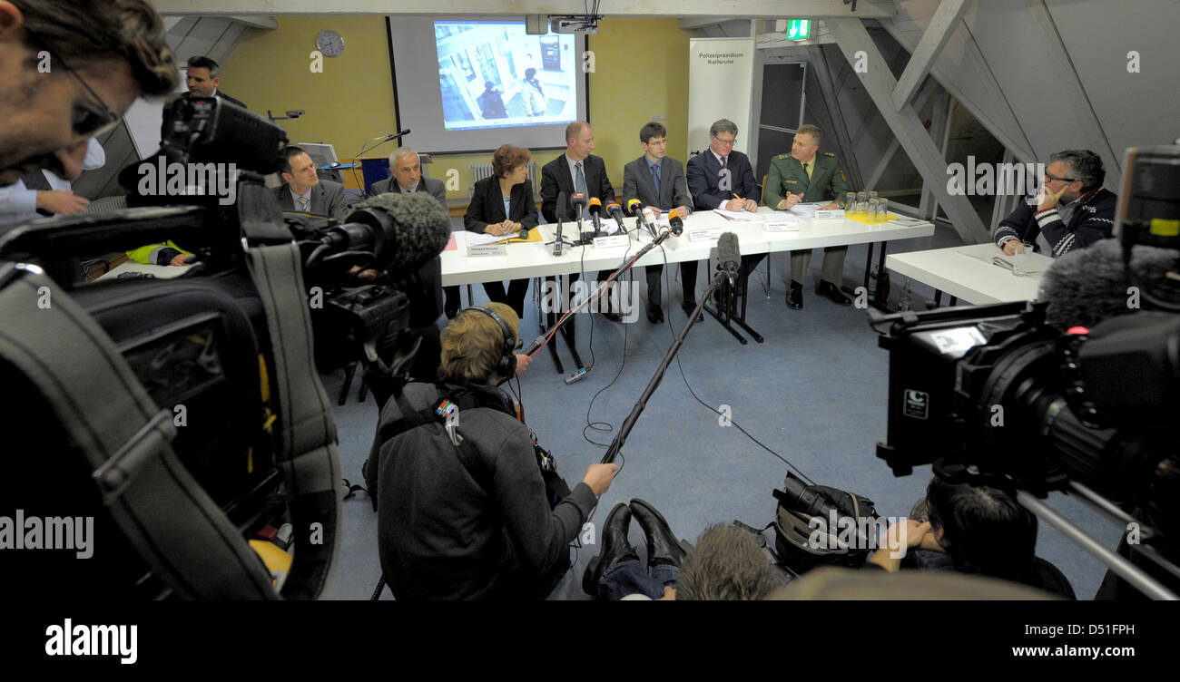 Police officers show screenshots with the two bank robbers from the security cam video during a press conference in Karlsruhe, Germany, 10 December 2010. In the course of a bank hold-up on a highly frequented shopping street, the police shot the two bank robbers, a man and a woman, dead. A female police officer was severely injured during the operation. The two robbers are held to  Stock Photo