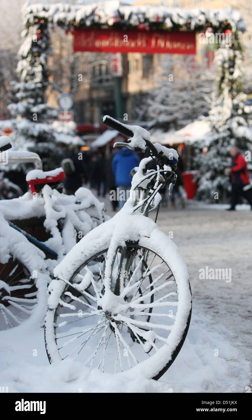 Snowcovered bicycles stand in front of a Christmas market in