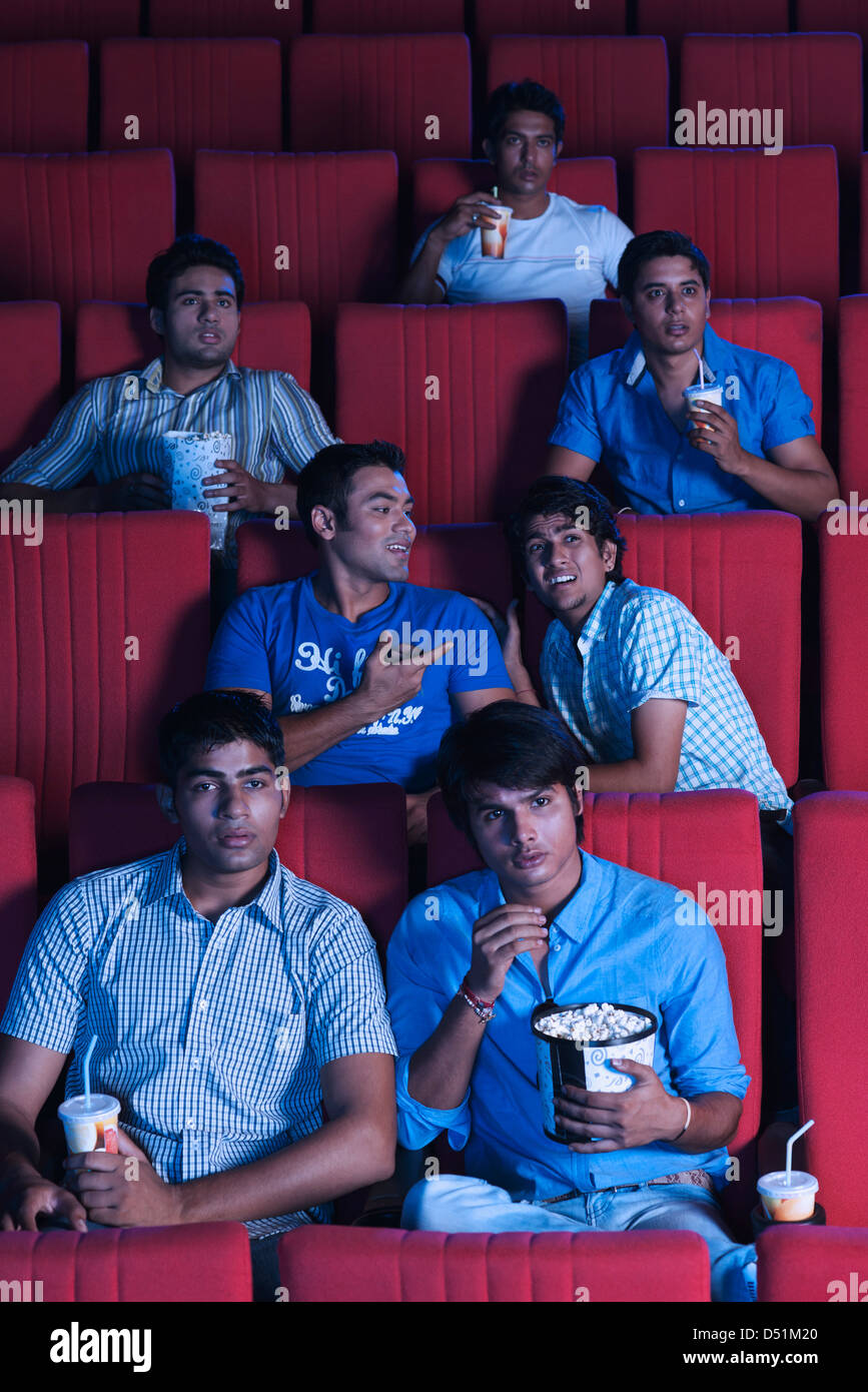 Youngsters enjoying movie with popcorns in a cinema hall Stock Photo