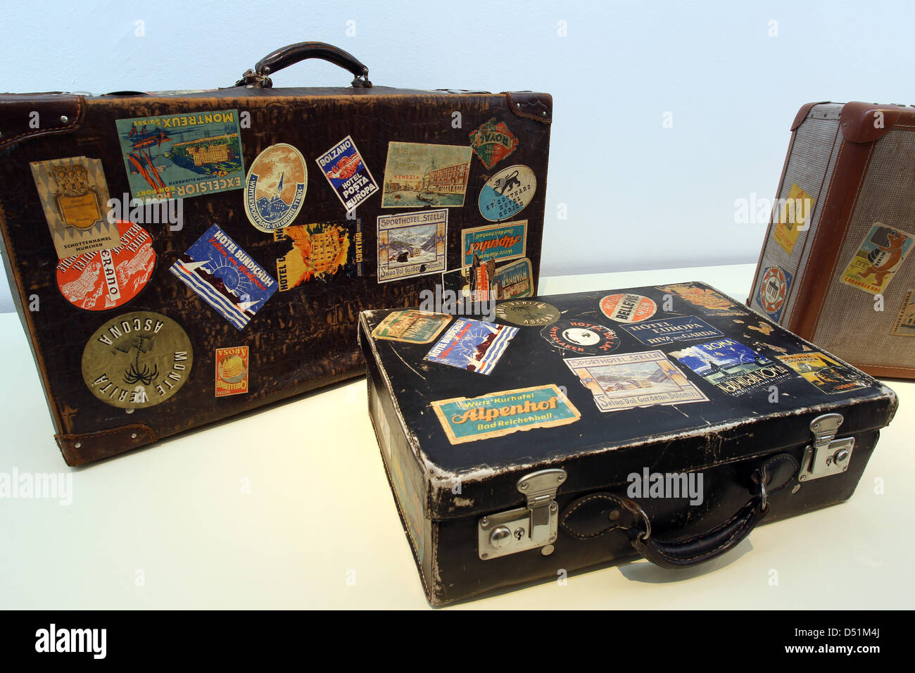 Suitcases bearing souvenir stickers are on display at a suitcase