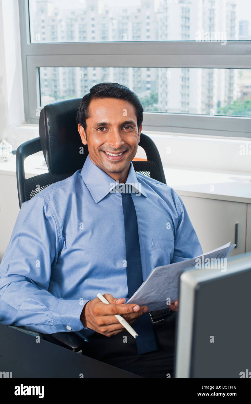 Businessman examining a document and smiling Stock Photo Alamy