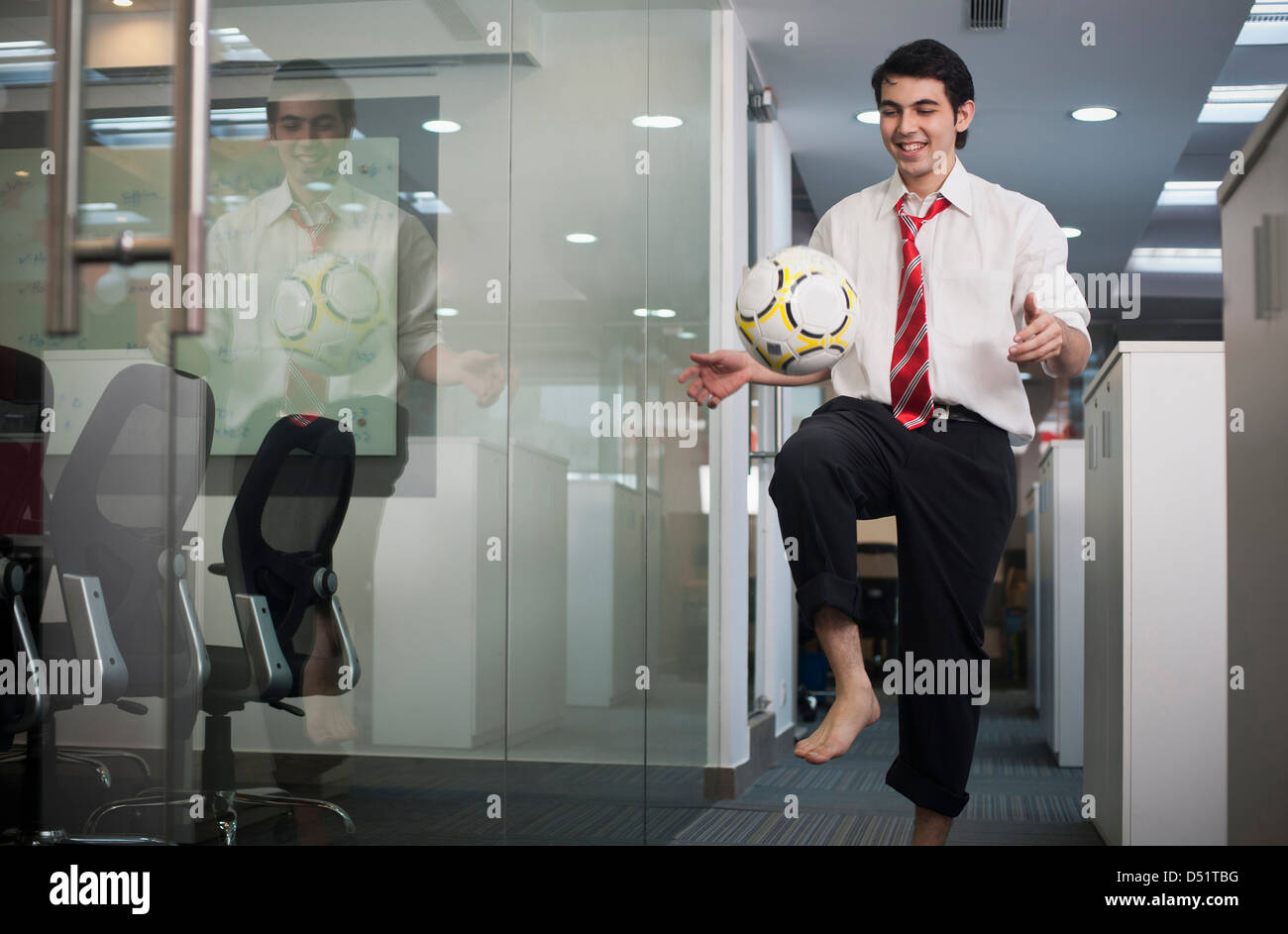 Businessman playing with a soccer ball in office Stock Photo - Alamy