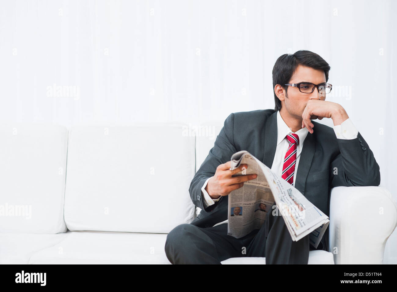 Businessman sitting on a couch and reading a newspaper Stock Photo - Alamy